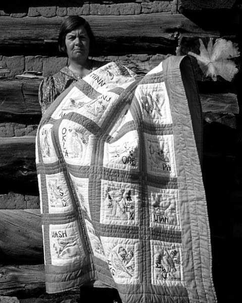 A woman holding a quilt, in black and white
